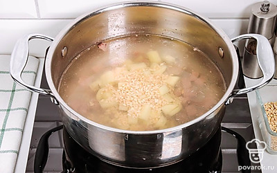 Доведите бульон до кипения. Выложите в него картофель и перловку, варите 5 минут.
