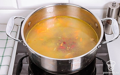 Переложите в рассольник овощную зажарку, фасоль и соленые огурцы. Посолите и поперчите.