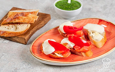 Смажьте маслом каждый ломтик багета. На одну половину выложите рыбу, рядом положите сыр. Сверху на сыр поместите кусочек помидора. Выложите на ломтик помидора 1 ч.л. песто.