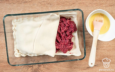 Духовку разогрейте до 180˚С. Тесто разделите на 2 части. Одну раскатайте и застелите форму для выпекания. Сверху положите фарш. Раскатайте вторую половину и выложите на фарш, хорошо залепив края. Смажьте слегка взбитым желтком и отправьте в духовку на 40 минут.