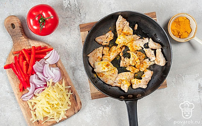 Налейте масло в сковороду, поставьте на огонь. Нарежьте куриное филе небольшими полосками и выложите на сковороду. Обжаривайте мясо до готовности. В конце приправьте филе солью, перцем и куркумой. Измельчите перец и помидоры небольшими ломтиками. Нашинкуйте лук перьями.