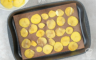 Разогрейте духовку до 180°C. Застелите противень пергаментной бумагой, сверху разложите картофельные ломтики. Поставьте противень в духовку и выпекайте чипсы 10-15 минут.