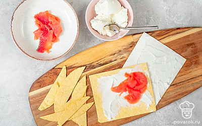 Начните приготовление. Филе семги нарежьте тонкими ломтиками. Затем возьмите одну лепешку и обильно смажьте ее сыром. Сверху выложите еще одну лепешку, слегка смажьте ее сыром и выложите рыбу равномерным слоем. Сверху положите оставшиеся лепешки, промазывая их творожным сыром.