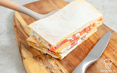 Закончите приготовление. Готовую закуску переложите на доску и накройте тарелкой. Уберите заготовку в морозилку на 1 час. Полученную закуску аккуратно подравняйте со всех сторон, чтобы срез был ровный. Затем разрежьте закуску пополам и положите одну половину на другую, скрепляя их творожным сыром. Полученное блюдо разрежьте на одинаковые квадратики.