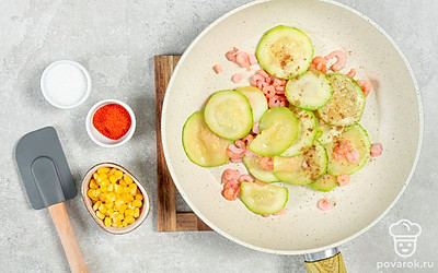 Подготовьте ингредиенты. В сковороду влейте и поместите ее на огонь. Когда масло нагреется, добавьте цуккини. Готовьте овощ 2 минуты, помешивая. Затем добавьте в сковороду креветки, кориандр, чили и соль, перемешайте. Чеснок пропустите через пресс и добавьте к ингредиентам. Потушите блюдо 2 минуты и затем снимите с огня. Готовые ингредиенты перемешайте с кукурузой и мягким сыром.