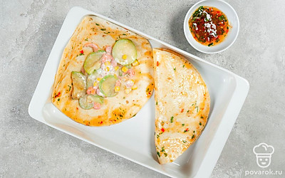 Приготовьте блюдо. Духовку разогрейте до 220 градусов. Форму для запекания смажьте несколькими ложками готового соуса. Кукурузную лепешку обмакните в соусе, а затем выложите на нее готовую начинку с цуккини. Сверните лепешку пополам и переложите в форму для запекания швом вниз. Проделайте то же самое с оставшимися ингредиентами.