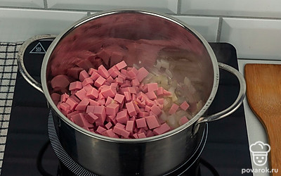 Обжарьте на растительном масле лук и колбасу.