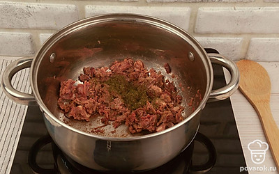 В кастрюлю с толстым дном (для небольших порций можно использовать глубокую сковороду) выложите тушенку, добавьте специи и поставьте разогреваться, чтобы растопился жир.