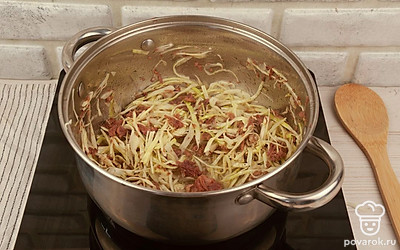 Когда жир станет жидким, выложите на тушенку капусту, перемешайте, закройте крышкой и поставьте тушиться на 15 минут на медленный огонь.