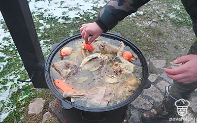 По истечению 3-х часов добавьте в казан лавровый лист, перец горошком, лук в шелухе и морковь. Продолжайте томить холодец 1 час.