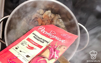 Добавьте в кастрюлю замороженные лесные грибы и красный молотый перец. Обжаривайте еще 5-7 минут.