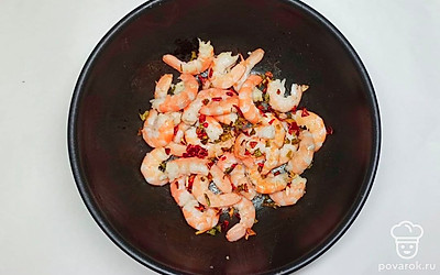 Чеснок очистите от кожуры, нарежьте на мелкие кубики. Раскалите сковороду, добавьте кунжутное масло, после креветки и обжарьте их в течение 3-5 минут. После посолите, добавьте перец чили и чеснок.