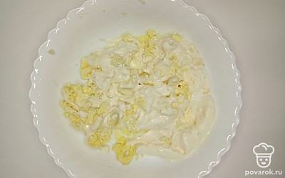 В тарелке соедините куриные желтки, измельченный чеснок, сливочный сыр и майонез. Все хорошо разомните вилкой, посолите и поперчите на свой вкус и перемешайте до однородности.