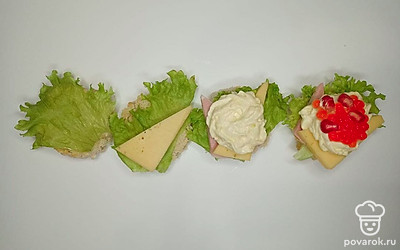 На подсушенные кусочки хлеба положите лист салата, тонко нарезанные кусочки ветчины и твердого сыра, подготовленный соус. В завершении украсьте красной икрой и зернами граната.