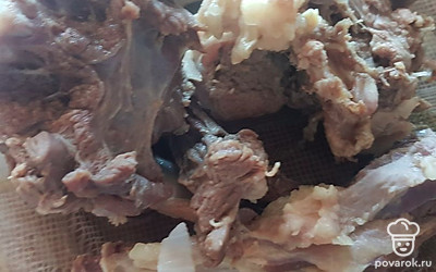 Готовое мясо достаньте из супа и разберите его. Отделите все косточки и нарежьте мякоть на кусочки. 