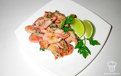 Блюдо подайте порционно на плоских тарелках, на каждую тарелку в середину положите горку готовых креветок. Лайм разрежьте на дольки и положите рядом с креветками на тарелку, сверху положите веточки петрушки, предварительно промытые под проточной водой.