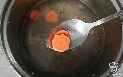 В кастрюлю налейте 1 литр холодной воды. Морковь нарежьте кружочками и добавьте в суп. Варите 10-15 минут. 