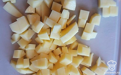 В кастрюлю налейте 2,5 литра холодной воды, поставьте на огонь. 3 средних картофелины нарежьте кубиком. Варите картошку 10 минут. Пока картофель варится. займитесь приготовлением фрикаделек.