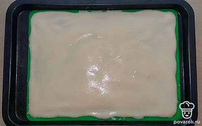 На дно противня выложите силиконовый коврик или пергаментную бумагу, смажьте маслом и вылейте тесто. Распределите его равномерно с помощью силиконовой лопатки.