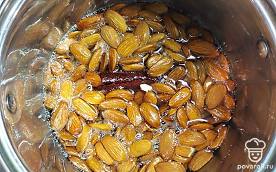 Когда вода закипит, добавьте в нее палочку корицы, засыпьте миндаль. Варите до момента, пока вода не выкипит. Миндаль начнет потрескивать, после этого можно добавить сахар.