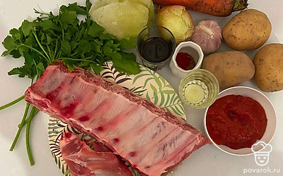 Замочите свиные ребрышки в глубокой миске на 20 минут. Возьмите лук, картофель, морковь и чеснок и почистите их от шелухи и кожуры. Сладкий перец и петрушку хорошо промойте и высушите.