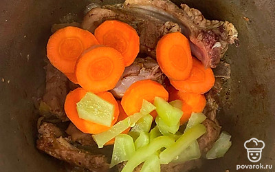 Возьмите казан и поставьте его на огонь выше среднего. Залейте в казан оливковое масло и добавьте в него свиные ребрышки. Влейте к ним соевый соус и посолите, добавьте приправы по вкусу, выдавите чеснок. Все хорошо перемешайте и тушите 3 минуты. Нарежьте лук и морковь кольцами. Перец нарежьте некрупной соломкой. Добавьте в казан лук, морковь и перец. Все хорошо перемешайте и тушите все на среднем огне 5 минут.