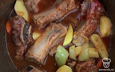 Картофель нарежьте небольшими кусочками. Добавьте его в казан и все хорошо перемешайте. Тушите 5 минут. Добавьте в казан томатную пасту и перемешайте, чтобы она распределилась по всем продуктам. Залейте в казан кипяченую воду так, чтобы она покрывала все содержимое. Тушите все 25 минут. Затем выключите огонь и дайте настояться шурпе под закрытой крышкой 15 минут. Перед подачей посыпьте зеленью.