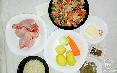Промойте куриные бедра и крыло. Очистите картофель и нарежьте небольшими кубиками. Морковь натрите на терке, а лук нарежьте кубиками. Продавите чеснок.