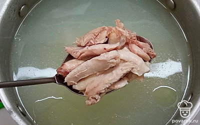 Налейте в кастрюлю воду, положите окорок, доведите до кипения, снимите пену, немного подсолите и варите 30 минут. Вытащите окорок, остудите, снимите с него кожу, отделите мясо от костей, порежьте его на кусочки и выложите их обратно в бульон.