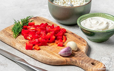 Займитесь измельчением продуктов. Творог хорошо разомните при помощи вилки. Болгарский перец мелко нарежьте. У свежего укропа отделите стебли, веточки измельчите. Зубчик чеснока очень мелко нарежьте, пропустите через пресс или терку с мелкими ячейками.