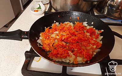 Для зажарки нарежьте кубиком лук и обжарьте его на раскаленной с маслом сковороде 3 минуты. Добавьте к луку морковь, жарьте 7 минут до мягкости моркови и лука.