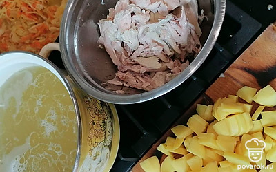 Нарежьте сырой картофель. Засыпьте картофель, куриное мясо и пассировку с капустой в бульон. Варите 15 минут.