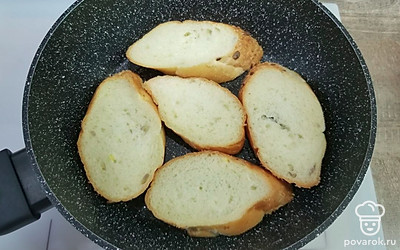 Нарежьте багет наискось острым ножом, чтобы получились овальные ломтики толщиной около полутора сантиметров. Выложите их на разогретую сковороду без масла и подсушите с обеих сторон до легкого золотистого оттенка и хрустящей корочки. Не пересушите, брускетта должна оставаться мягкой внутри. На горячую сковороду выложите креветки и прогрейте 1 минуту. Горячие ломтики багета натрите долькой чеснока и сбрызните оливковым маслом.