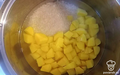 Промойте рис и выложите его в кастрюлю. Залейте рис теплой водой. Картофель нарежьте на небольшие кусочки и поместите в кастрюлю к рису. Отварите до готовности.