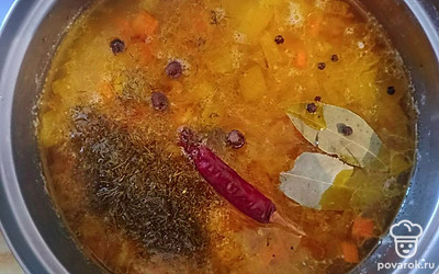 В кастрюлю с готовым картофелем добавьте зажарку, рассол, специи, Чили и лавровый лист. Всё перемешайте и варите 5 минут, а затем дайте настояться ещё 10 минут.