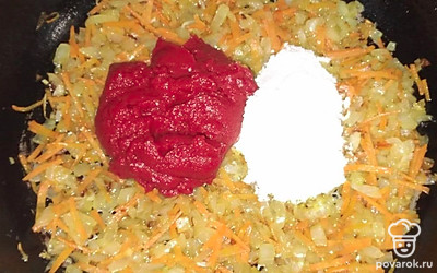 Лук нарежьте небольшими кубиками, отправьте обжариваться на разогретой сковороде. К нему добавьте тертую на терке морковь, обжаривайте около 1 минуты. Далее добавьте томатную пасту, муку и перемешайте.