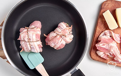 Приготовьте рулеты с козьим сыром. Посередине каждого кусочка эскалопа выложите по кусочку сыра и сверните. Оберните каждый рулет двумя ломтиками бекона и завяжите кулинарной нитью. Сковороду поставьте на средний огонь и выложите на него рулеты. Жарьте 10-15 минут, постоянно переворачивая. После готовности удалите кухонную нить.