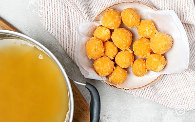 Приготовьте закуску. Разделите тесто на шарики размером с грецкий орех. Обильно обваляйте в муке, излишки стряхните. Опускайте шарики в кипящее масло. Жарьте до золотистости и выкладывайте на салфетки, чтобы они впитали лишний жир.