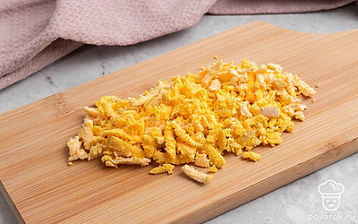 Очистите яйца от скорлупы, аккуратно разрежьте вдоль на две половины и удалите желтки. Белки отложите в сторону, а желтки измельчите.