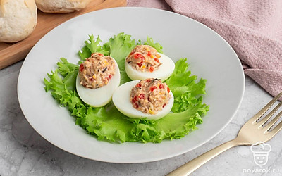 Возьмите красивую тарелку, выложите её листьями салата, а затем положите сверху готовые фаршированные яйца. Всё готово, можно подавать!