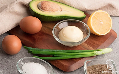 Приготовьте необходимые ингредиенты. Яйца отварите. Авокадо и лимон помойте и разделите пополам. Зеленый лук помойте