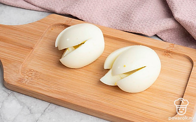 Очистите яйца от скорлупы, а затем аккуратно сделайте на каждом крестообразный разрез примерно до середины. С осторожностью достаньте желтки, а белки отложите ⎯ они понадобятся чуть позже.