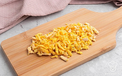 Аккуратно очистите варёные яйца от скорлупы, разрежьте каждое вдоль на две половинки и достаньте желтки. Отложите белки в сторону, а желтки хорошенько измельчите.