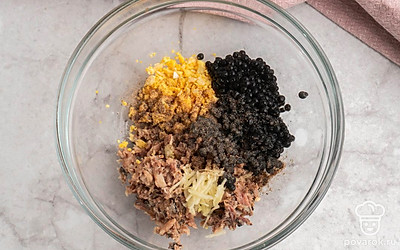 Натрите чеснок на терке или воспользуйтесь давилкой для чеснока. В глубокой удобной миске смешайте желтки, икру и чеснок. Добавьте немного черного молотого перца и щепотку соли. Тщательно всё перемешайте.