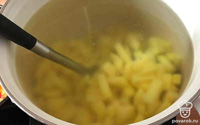 Выложите в кипящую воду картофель, пшено и сок из консервированной горбуши. Дайте прокипеть 5 минут. 