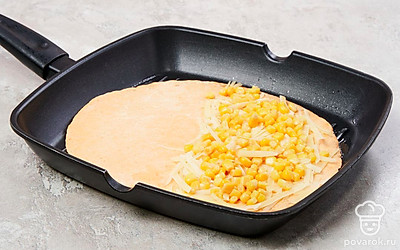 Обжарьте тортильи с кукурузой. Сковороду поставьте на умеренный огонь, выложите одну лепешки и обжарьте с одной стороны 10-20 секунд. Затем переверните и положите на одну половину тертый сыр и немного кукурузы. Сверните лепешку пополам и слегка прижмите. Обжарьте тортилью с обеих сторон до румяности и переложите на тарелку. Таким образом пожарьте все тортильи с кукурузой и тертым сыром.