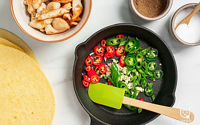 Приготовьте начинку. Сначала обжарьте подсоленные кусочки индейки на капле масла по 5 минут с обеих сторон. Затем остудите жареное филе и разберите на волокна. В сковороде из-под индейки обжарьте перец халапеньо, измельченные зубчики чеснока, зеленый лук. Посыпьте кориандром и кумином. Жарьте на среднем огне несколько минут до мягкости перца.