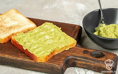 Приготовьте тосты. Хлеб подсушите в тостере. Авокадо разомните вилкой до кашеобразного состояния, добавьте половину соли, перемешайте. Намажьте получившуюся пасту на хлеб.