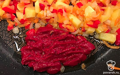 Затем сдвиньте овощи в сторону, добавьте в сковороду еще масла, положите томатную пасту, прогрейте ее и смешайте с овощами, потушите еще несколько секунд.