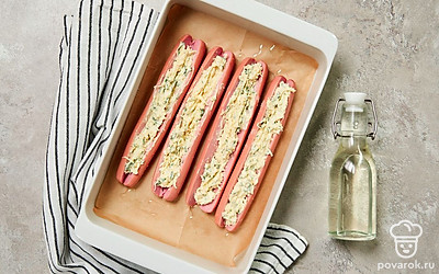 Запеките сосиски. Форму для запекания смажьте маслом. Выложите сосиски в форму. Каждую наполните начинкой по надрезу и запеките в течение 15 минут.